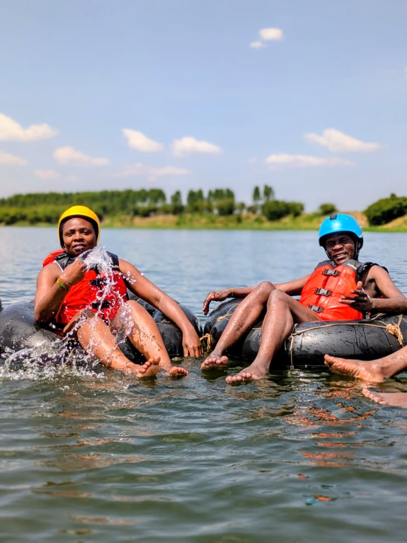 Two tubers laughing and splashing on the Nile, water flying, red life vests
